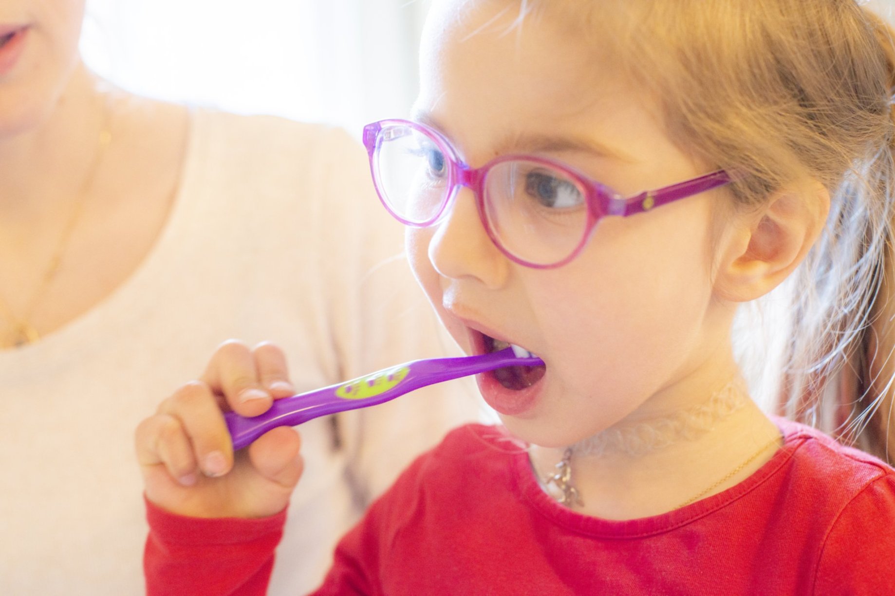 Mädchen mit Brille putzt sich die Zähne