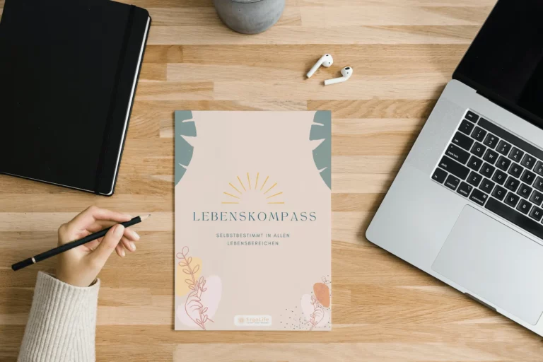 Heft „Lebenskompass“ auf einem Holztisch zwischen Laptop und Tablet