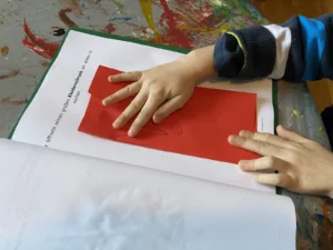 Kinderhände falten rotes Papier auf der Vorlage der Faltgeschichte