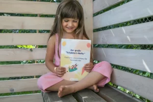 Mädchen sitzt auf einer Bank und liest im großen Schulstarthelfer