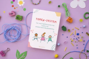 Heft „Token-System“ auf lila Hintergrund mit Bastelmaterial